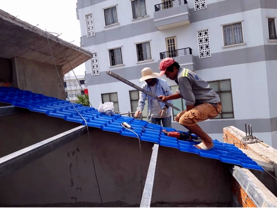 Thợ thi công đang lắp đặt các tấm lợp mái tôn lên hệ khung thép